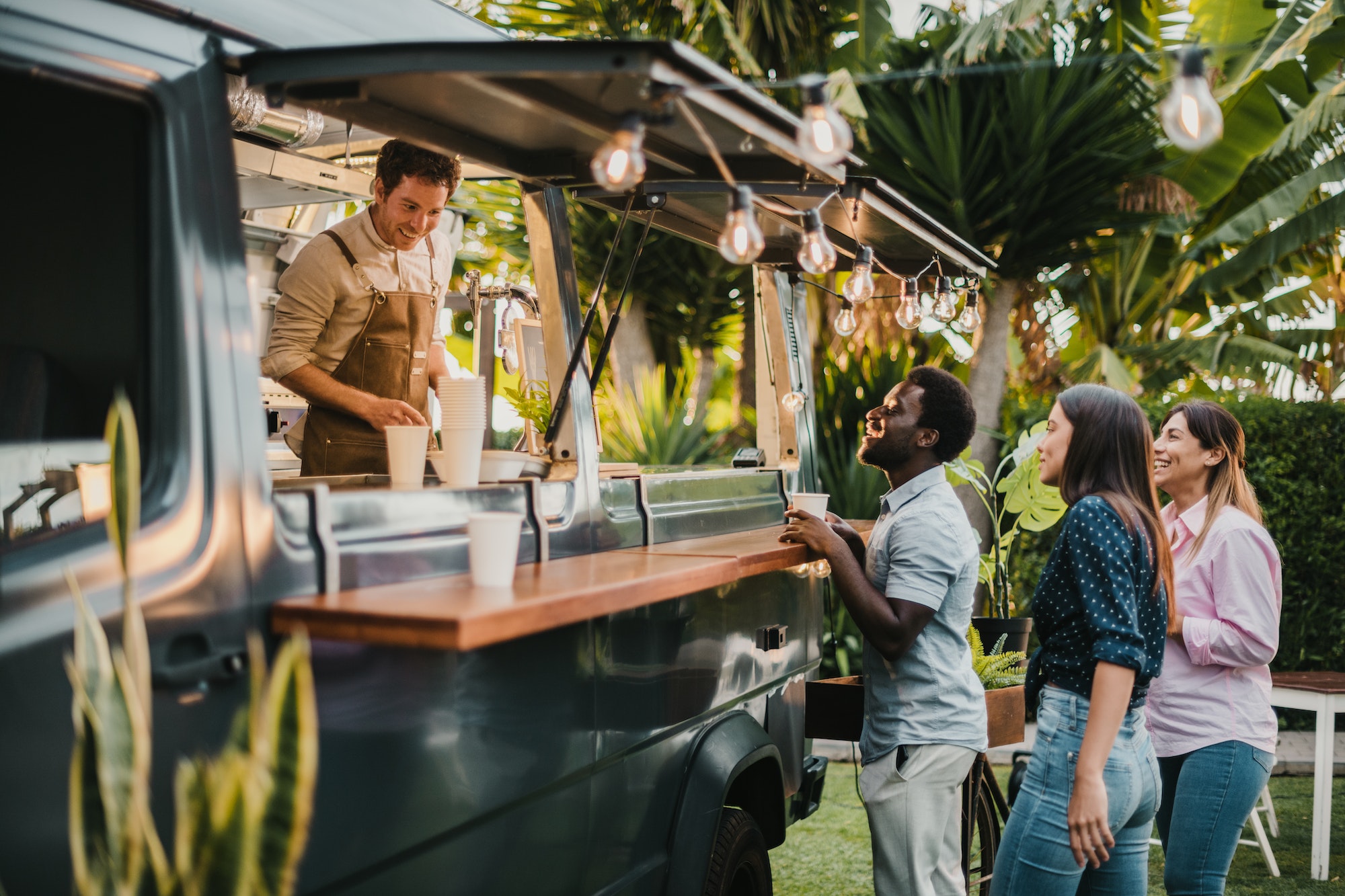 Multiracial friends making order to seller in food truck