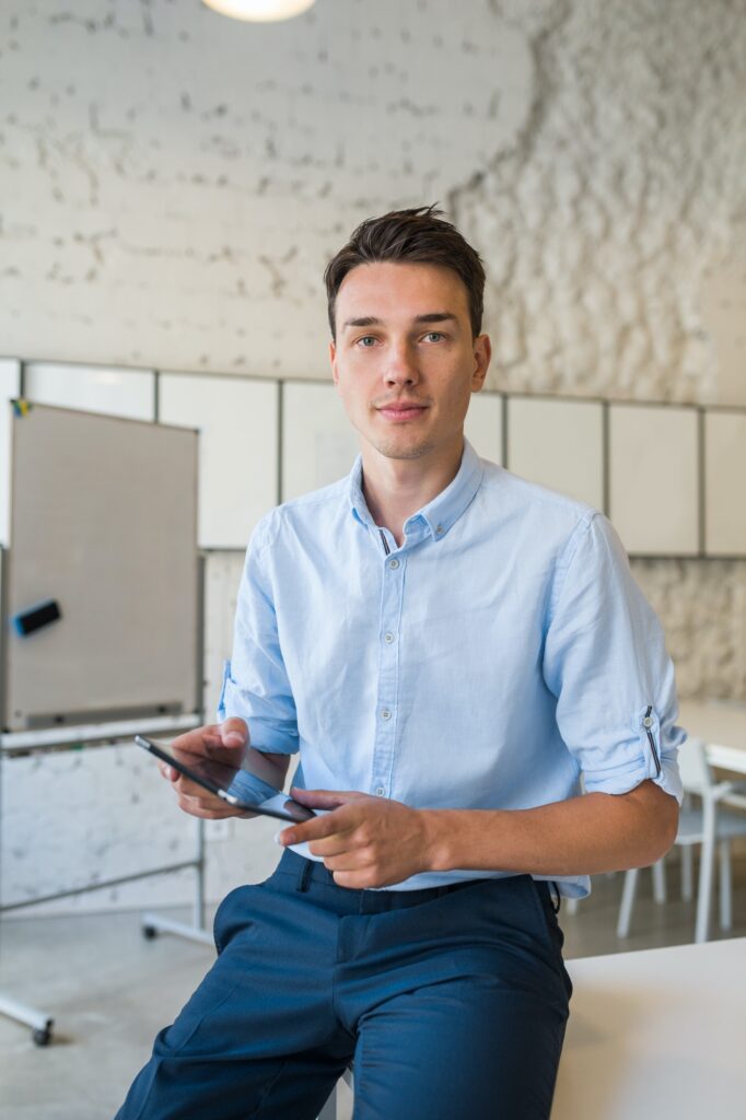 young stylish smiling man in co-working office, startup freelancer holding using tablet